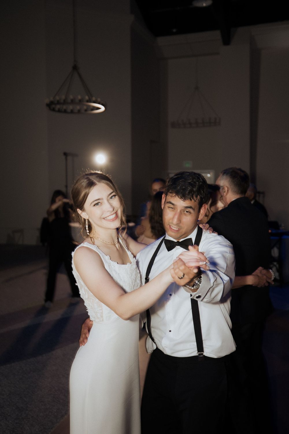 A couple dancing together at a wedding reception, with the bride in white and groom in formal attire.