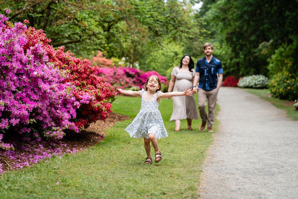 Daughter running towards the camera while mom and dad look on.