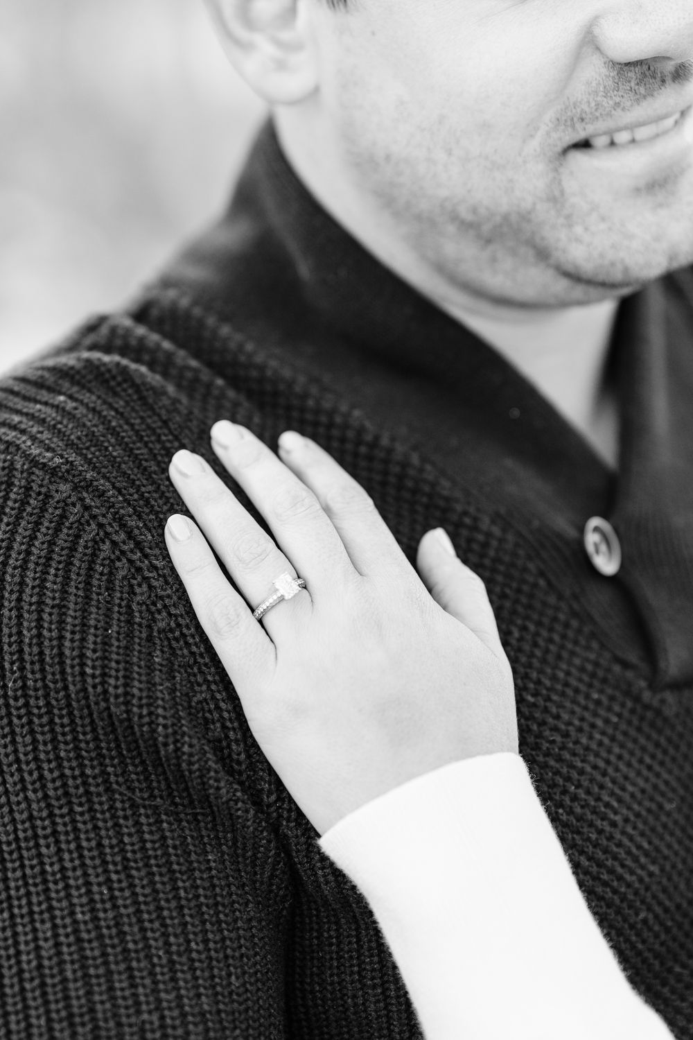 Close-up view of hands displaying white gloves against a dark knit sweater background.