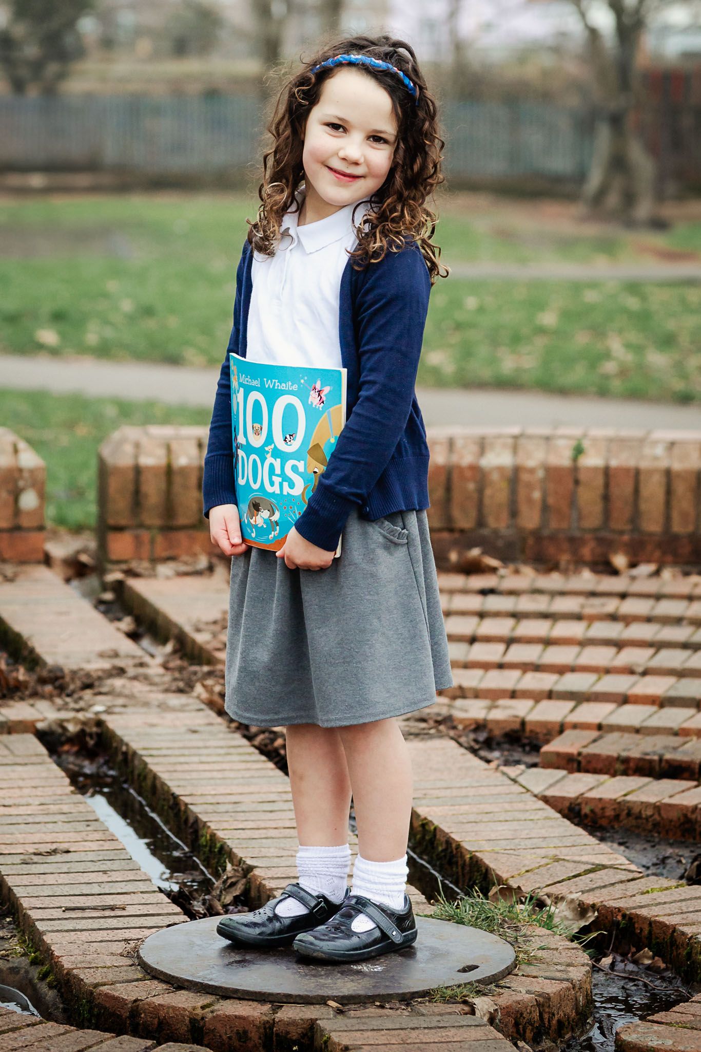 A school girl holds her favourite book and smiles to camera during a school photo mini session. Bristol school photographer