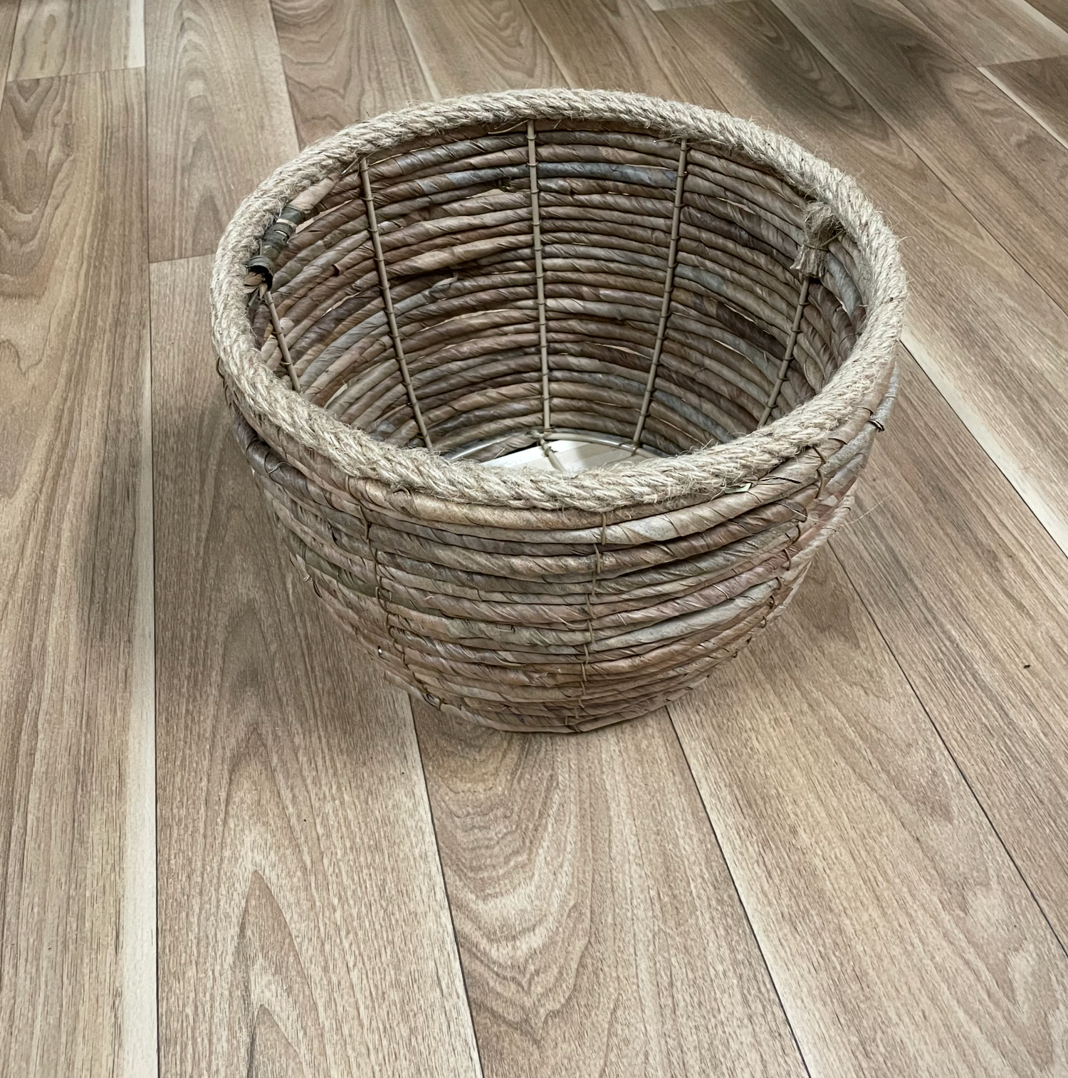 Round wicker basket shown from multiple angles on wooden floor.
