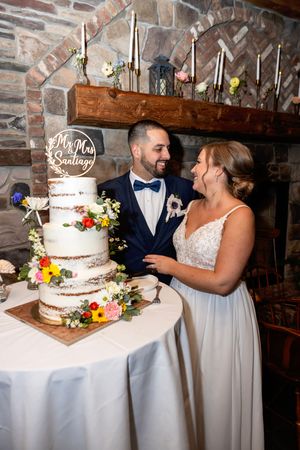A traditional three-tiered wedding cake with flowers adorns a table as newlyweds NJ wedding photographer | best NJ wedding photographer