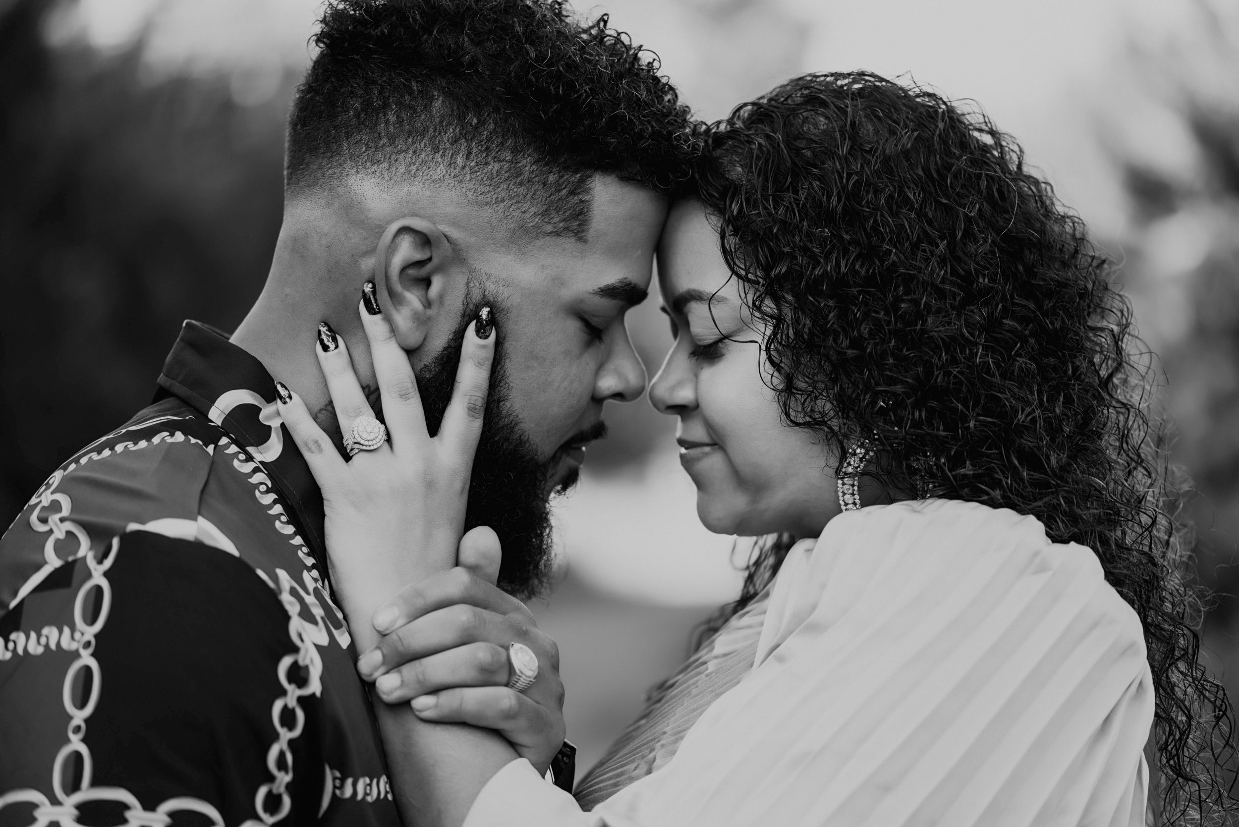 Black and white photo of a romantic couple sharing an intimate moment, touching foreheads with eyes closed.