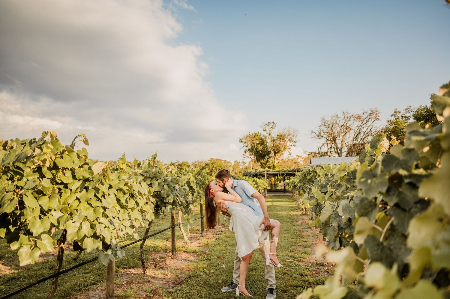 A couple sharing an intimate moment in a sunlit vineyard.