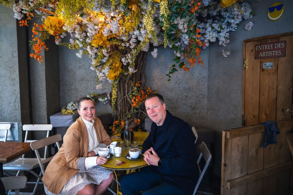 People gather for drinks and socializing inside a rustic pub decorated with autumn flowers and wooden accents.
