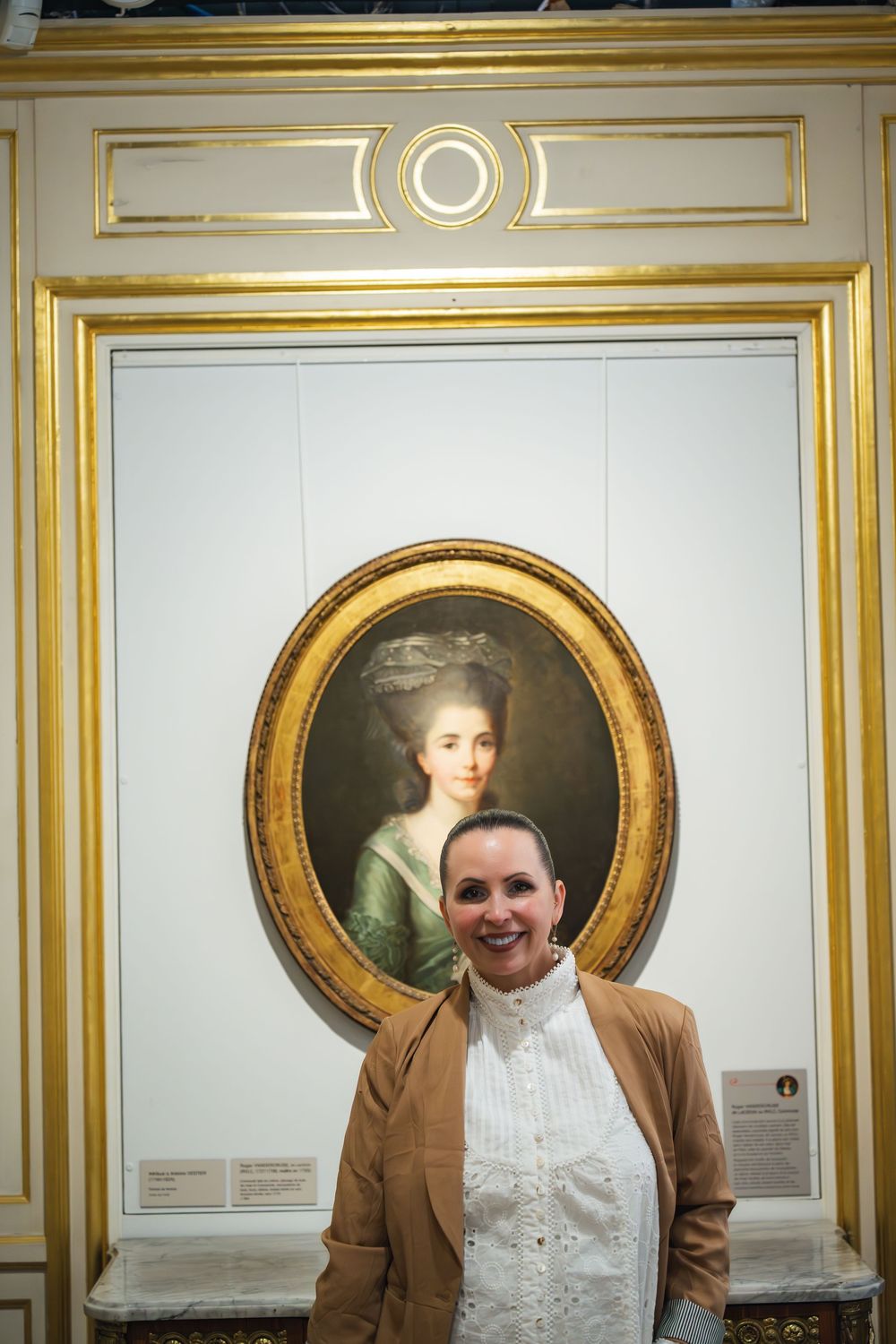 An elegant gallery wall with ornate gold frame moldings showcases a classic 18th century portrait painting.
