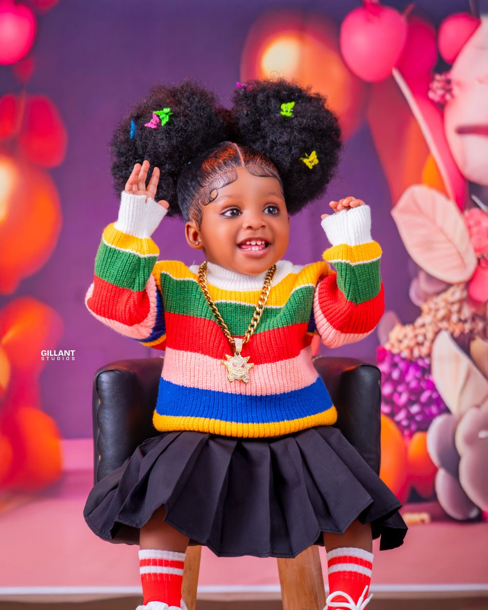 Colorful holiday card photoshoot featuring child in festive striped sweater and tulle skirt against pink bokeh backdrop.