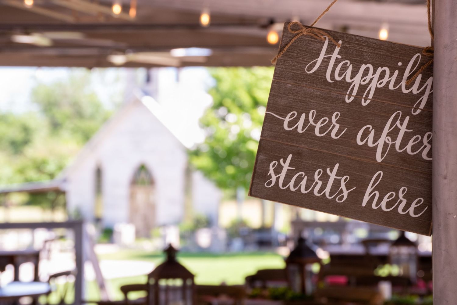A rustic wedding venue decorated with hanging lights and chalkboard signs displaying romantic messages.