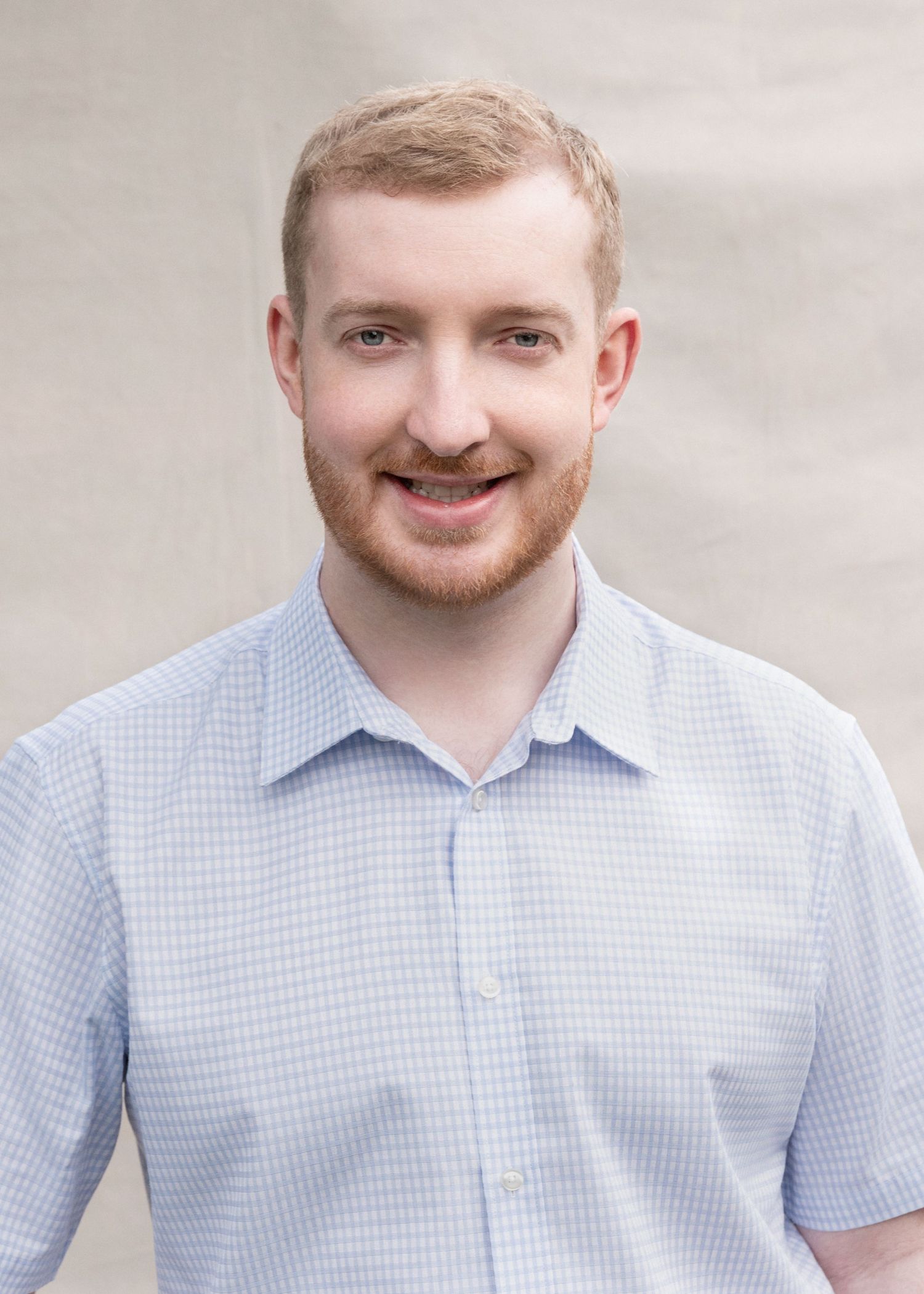 A person in a light blue checkered shirt smiles warmly at the camera in a progressive sequence of expressions.
