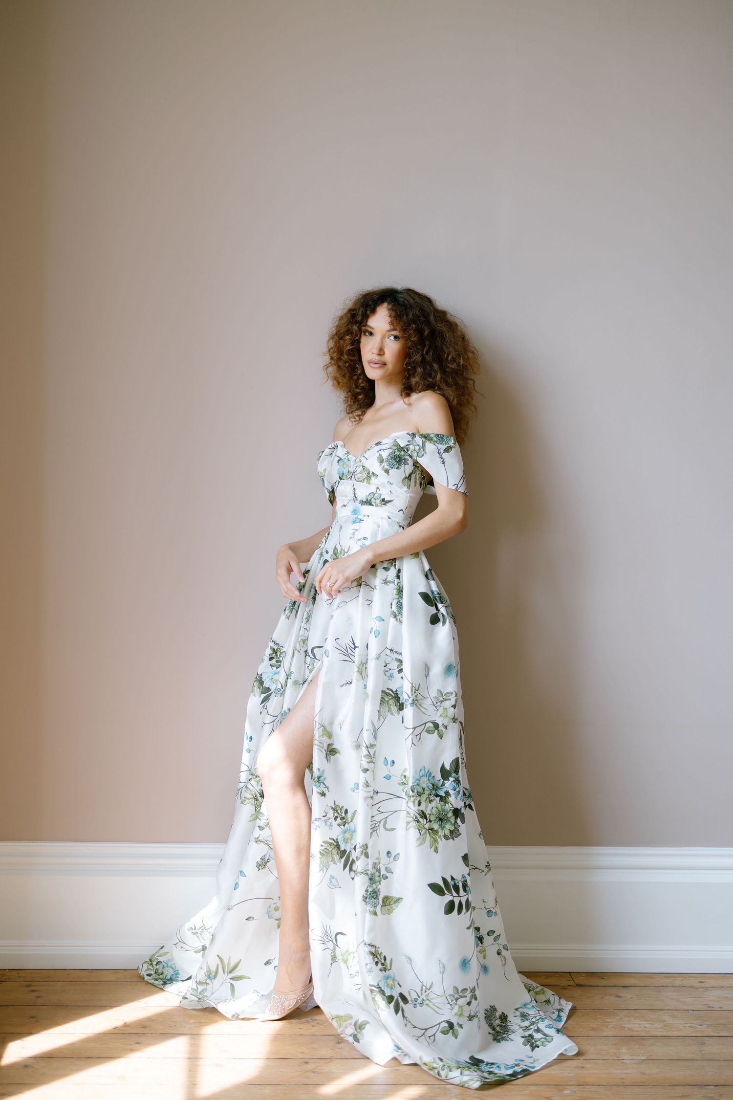 A delicate white and blue floral dress flows gracefully in a minimalist indoor setting.
