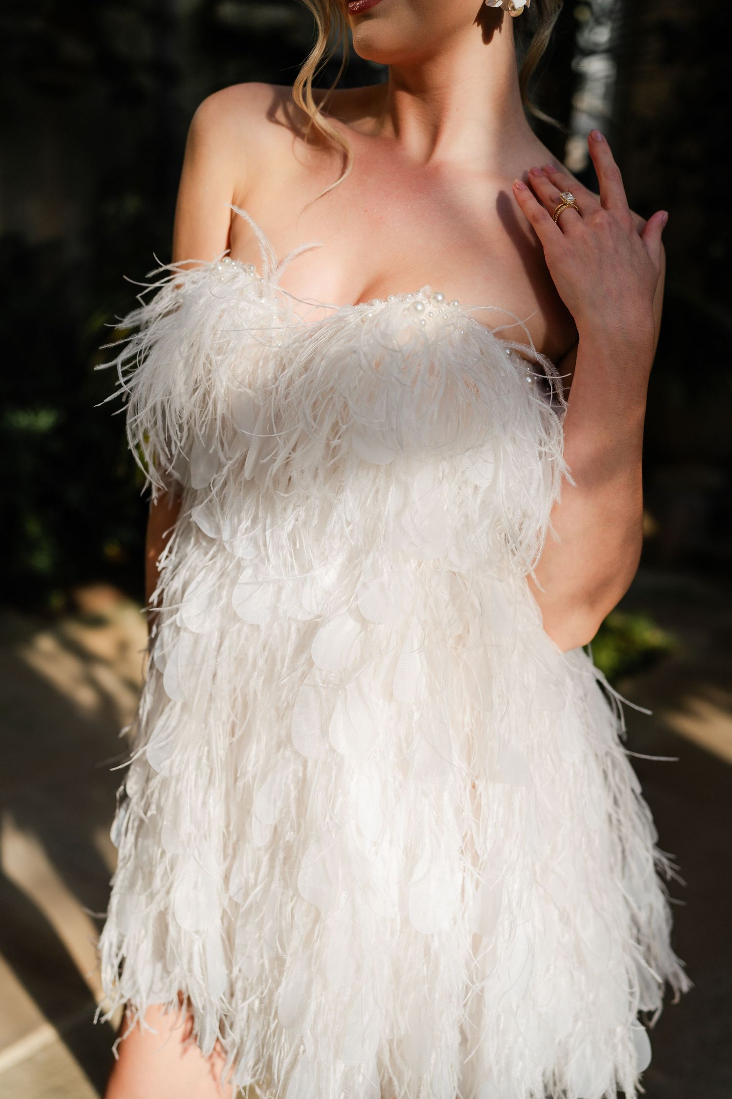 Close-up details of a white feathered wedding dress with delicate textures and layers.