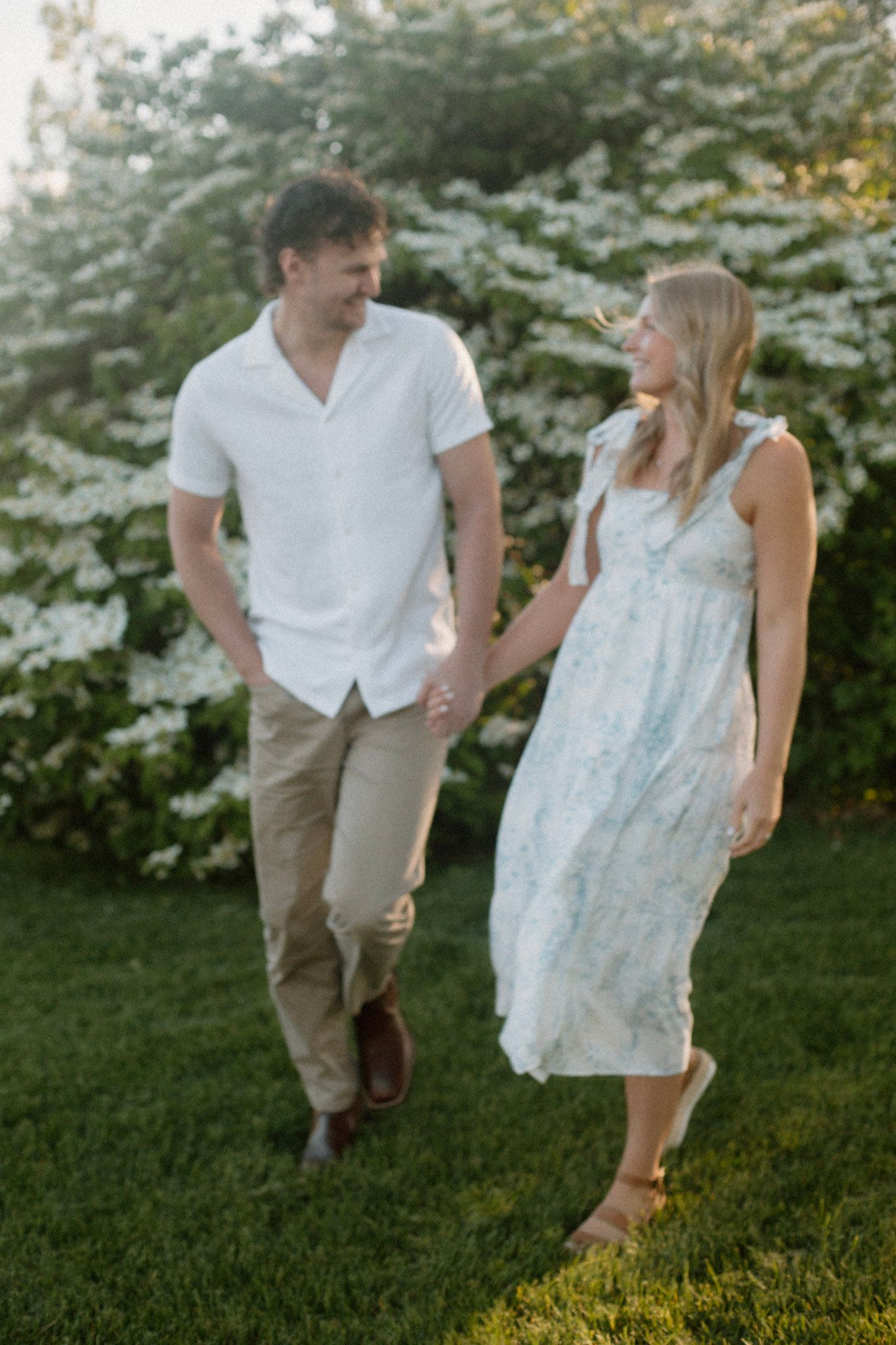 Couple walking and looking at each other during their engagement session at Millennium Park in Grand Rapids MI.