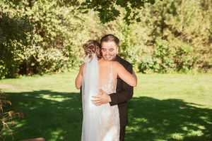A joyful couple embraces outdoors on a sunny day in a lush garden setting with natural greenery in the background.