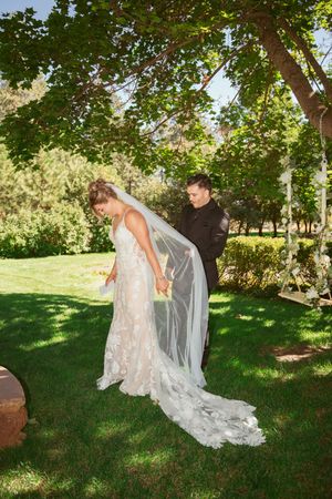 A couple shares an intimate moment in a sunlit garden as they prepare for their wedding ceremony.