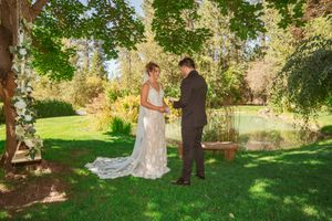 A couple shares an intimate moment during their outdoor garden wedding ceremony surrounded by lush greenery and trees.