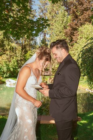Newlyweds sharing a playful moment with beverages in an outdoor garden setting.