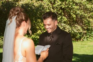 A loving exchange of vows during an outdoor wedding ceremony as the couple reads from paper in a sunlit garden.