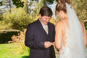 A couple shares a tender moment during their outdoor wedding ceremony as they exchange vows in a garden setting.