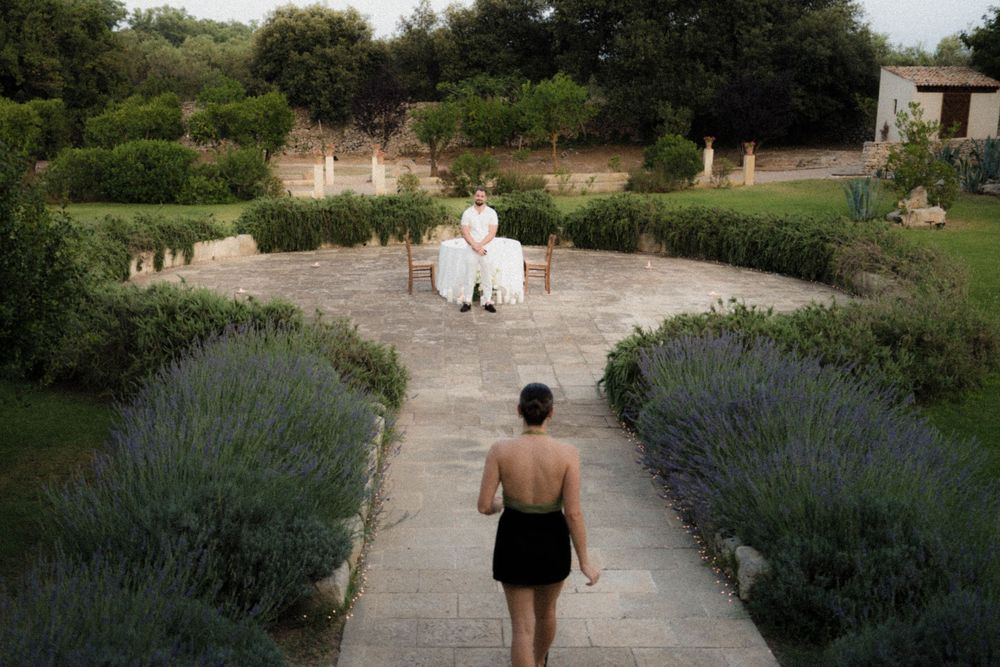 A path lined with blooming lavender leads through a tranquil garden setting on a sunny day.