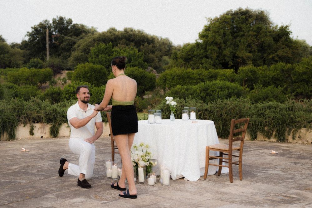 A candid moment of two people at an outdoor dining setup with a white tablecloth and floral decor.