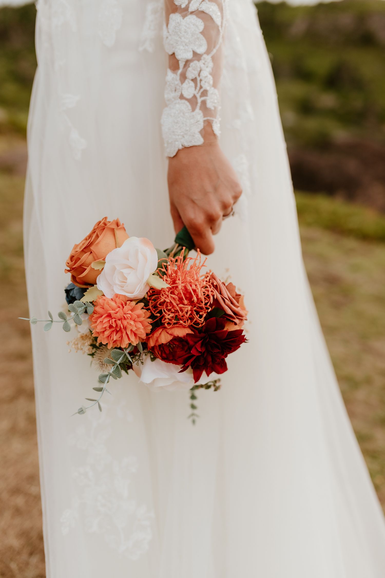 close up of a bride's hand holding her bouquet by her side