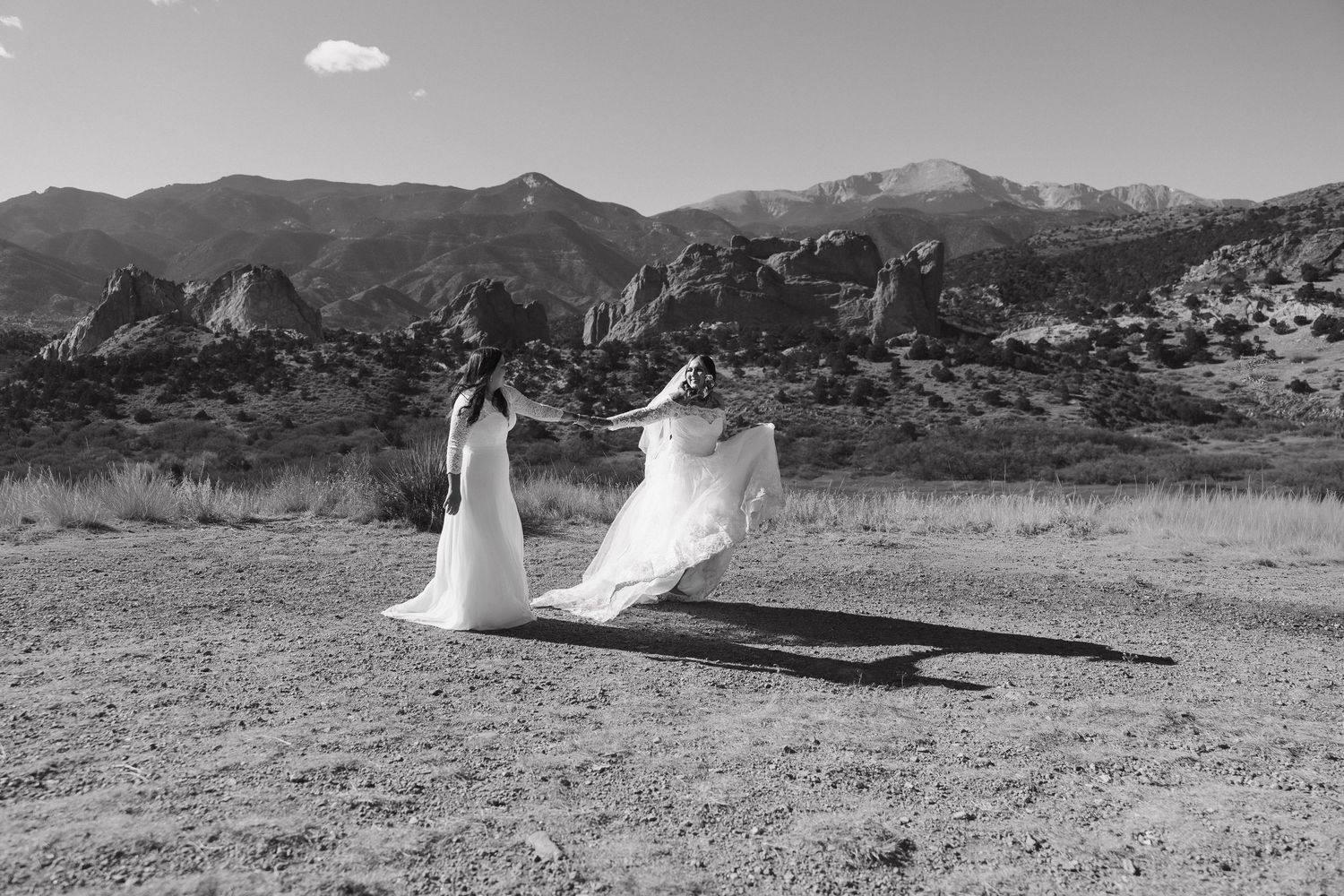 A black and white panoramic view of a desert landscape with mountains and scattered white fabric in the foreground.