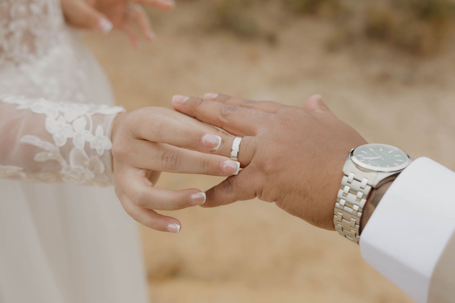 Close-up view of hands exchanging wedding rings during a romantic outdoor ceremony.