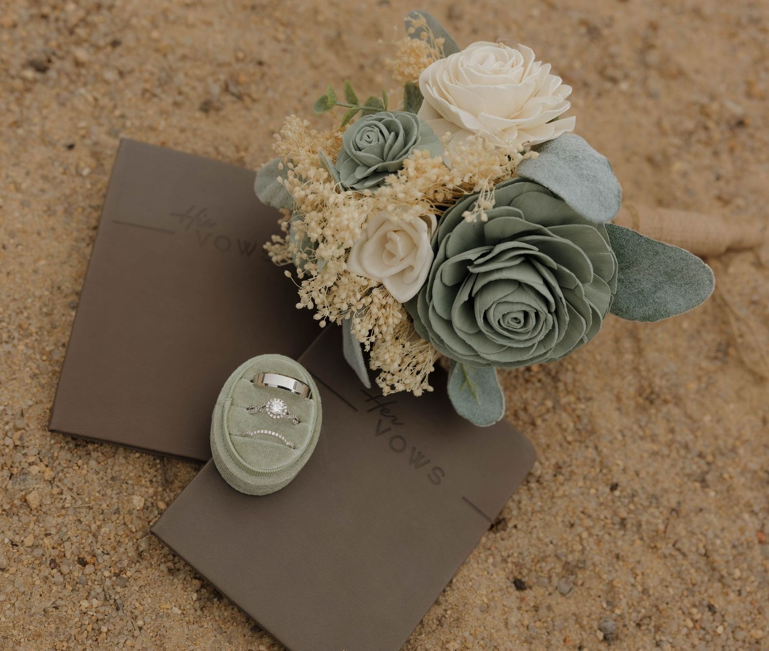 Elegant wedding invitation suite in sage green and cream with dried flowers and eucalyptus leaves on textured background.