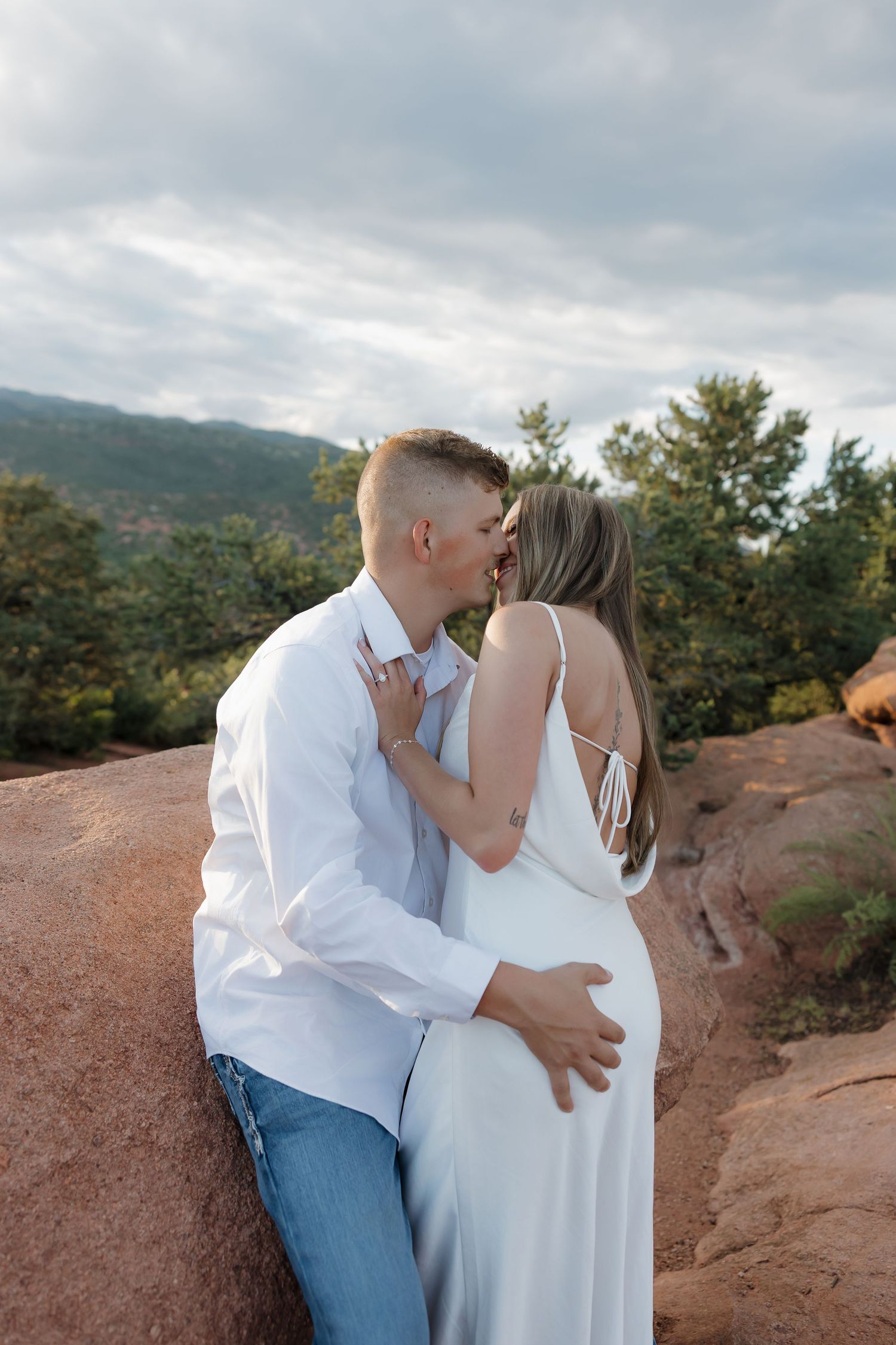 A romantic couple shares tender moments on a scenic mountain overlook during sunset.