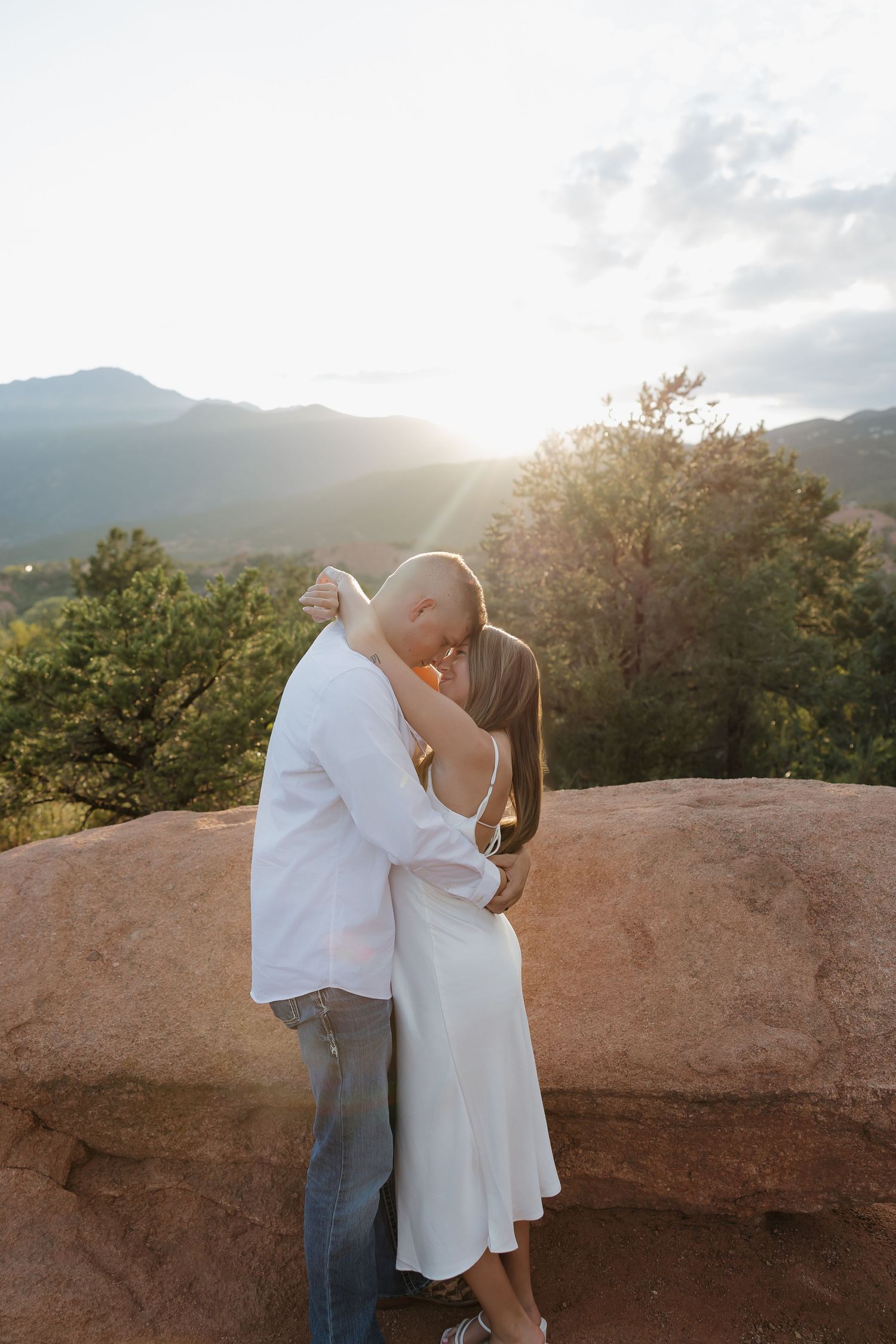 A couple shares a romantic moment at sunset against a mountainous backdrop at Garden of the Gods in Colorado Springs.