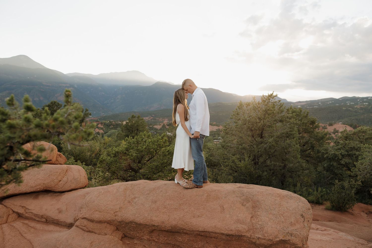 Couple embracing on red rocks during sunset at Garden of the Gods in Colorado Springs.