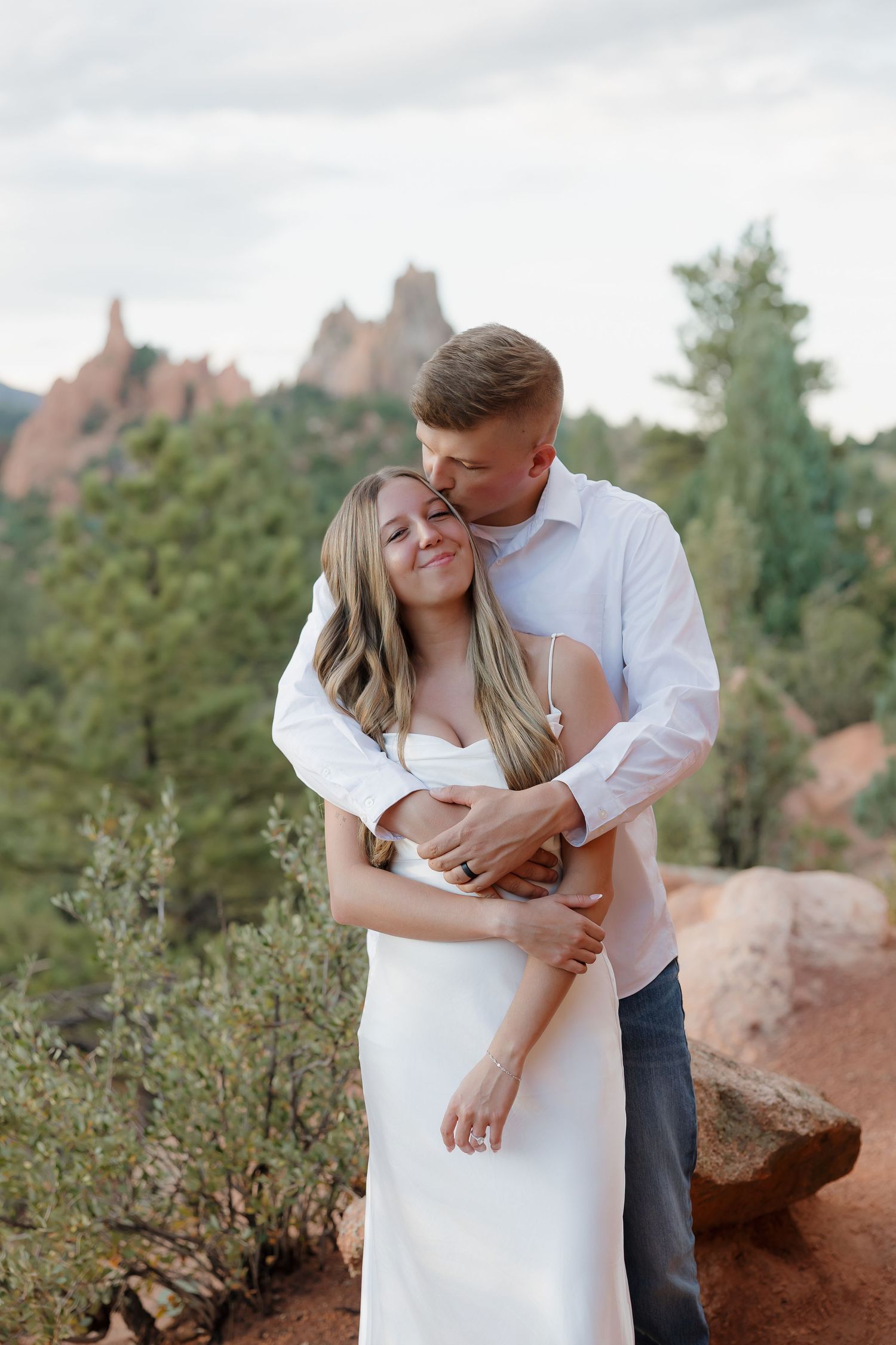 A romantic couple embraces among red rocks and desert foliage at Garden of the Gods in Colorado Springs.