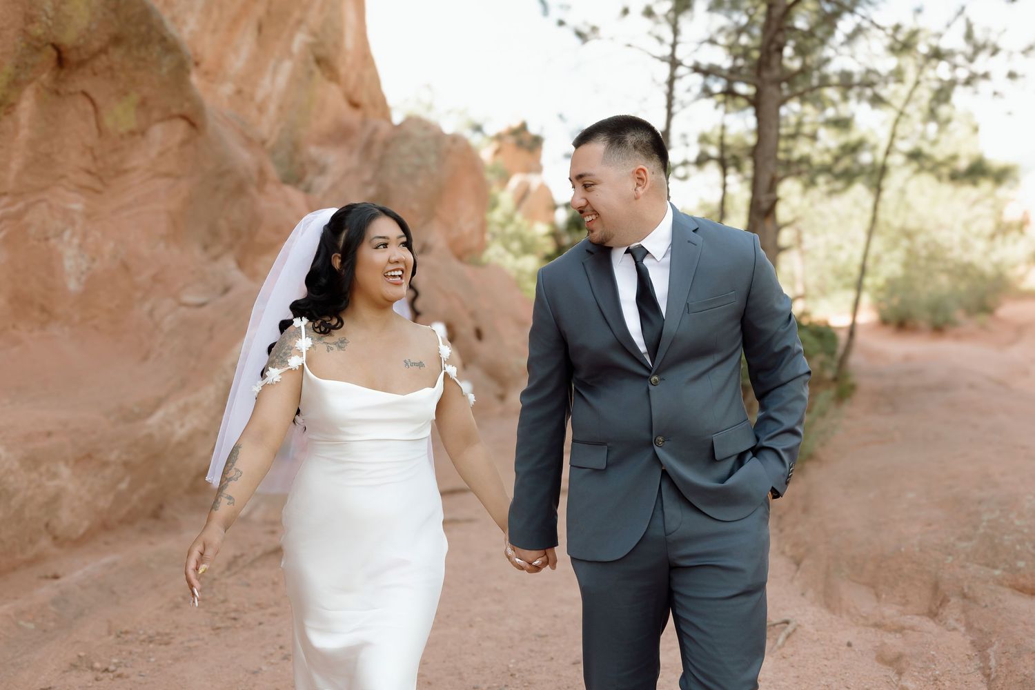 Bride and groom share candid moments together against a backdrop of stunning red rock formations in a desert landscape.
