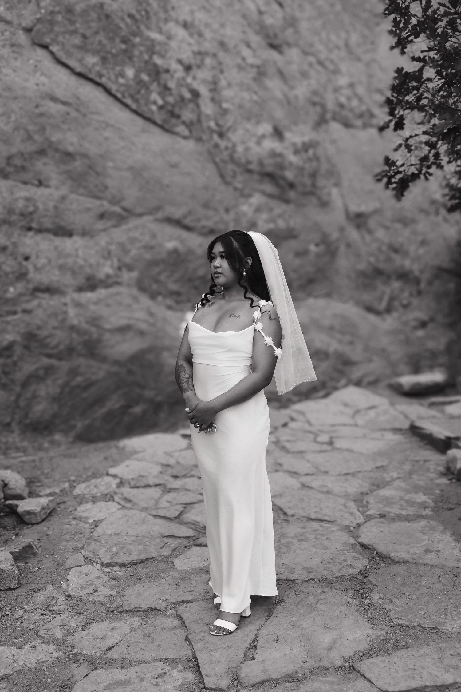 Black and white wedding portraits of bride on textured rock formations in dramatic lighting.