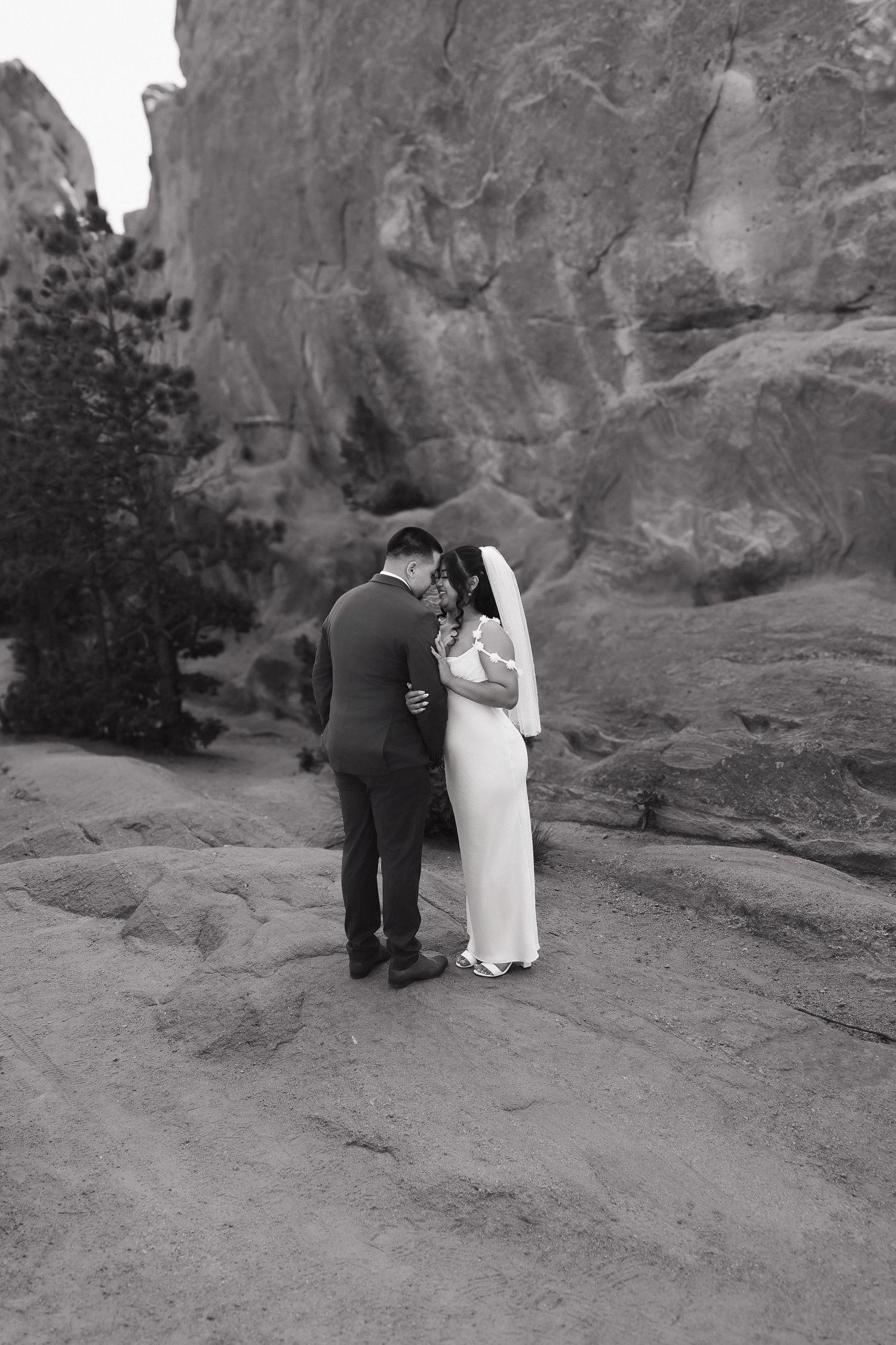 Wedding couple in black and white sharing tender moments against dramatic rock formations.