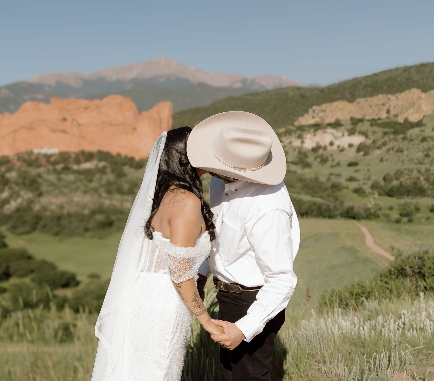 A romantic mountain wedding photo at Garden of the Gods with Pikes Peak visible in the background.