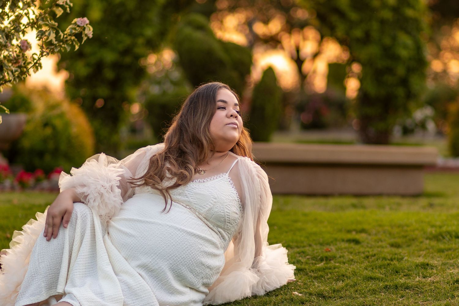 A person in a white dress twirls gracefully in a sunlit park during golden hour.