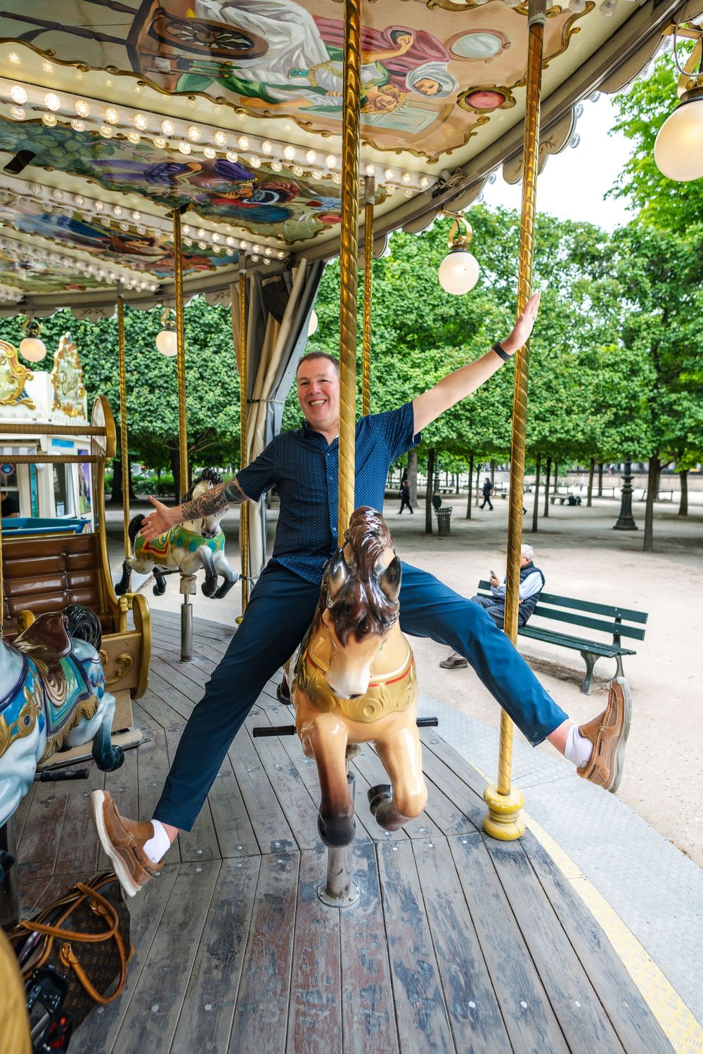 Playful scene on a vintage carousel with decorative animals and an ornate ceiling in a lush park setting.