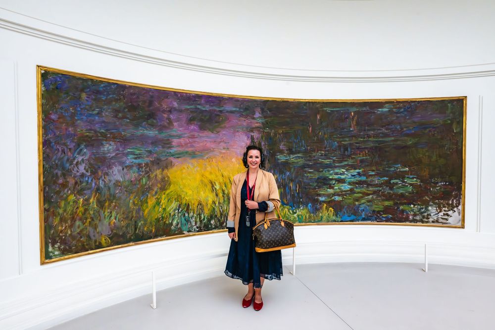 Tourists admire Claude Monet's large-scale Water Lilies paintings displayed in curved gallery walls at a museum.