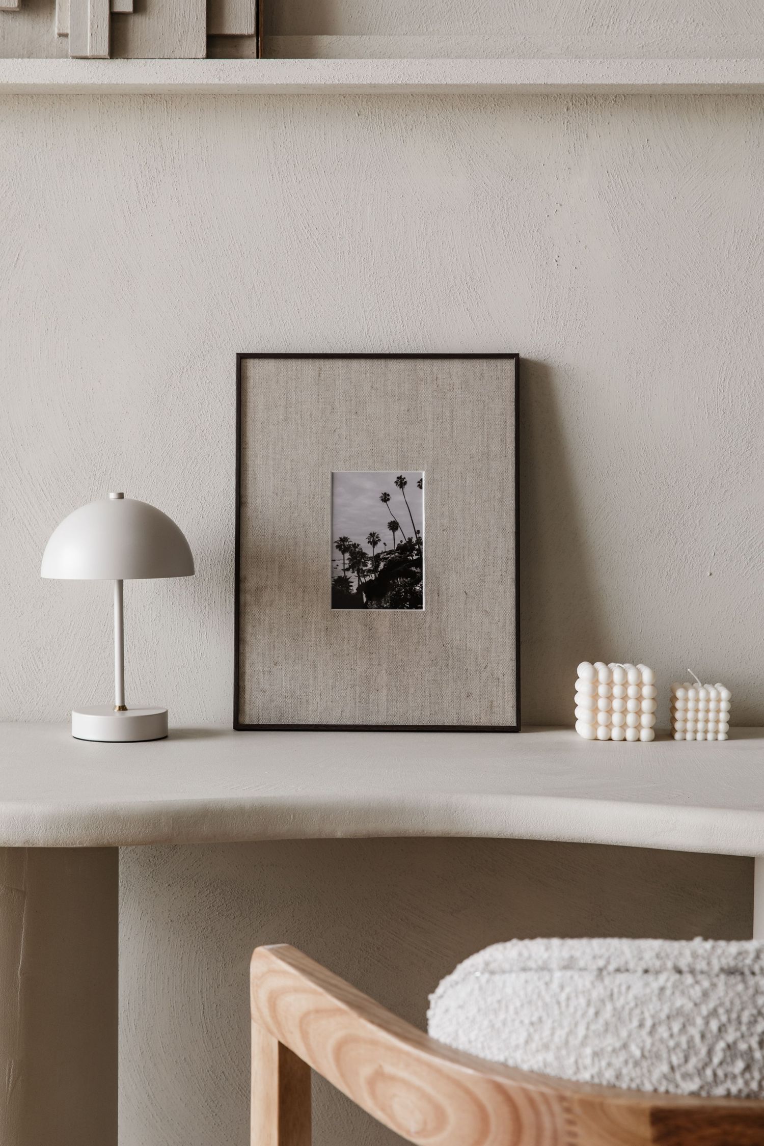 Een reisfoto met palmbomen in een donker houten lijst met een linnen passe partout. Staat in een beige interieur.