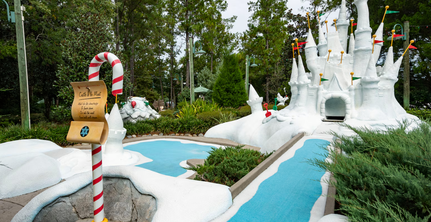 Whimsical winter-themed water slide with candy cane decorations and a white castle backdrop in a Disney theme park.