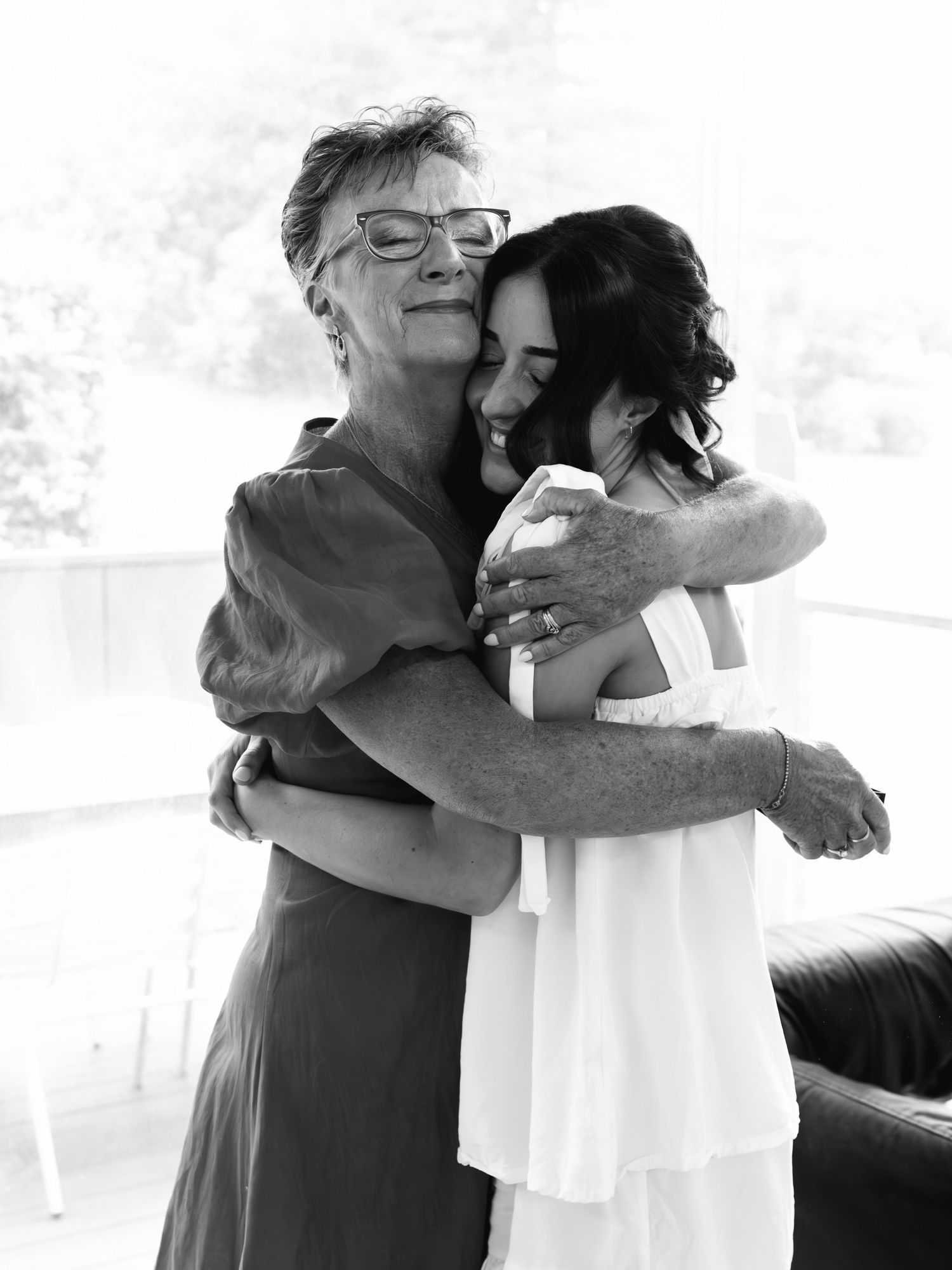 Black and white photograph showing two people sharing an intimate embrace with closed eyes and warm smiles.