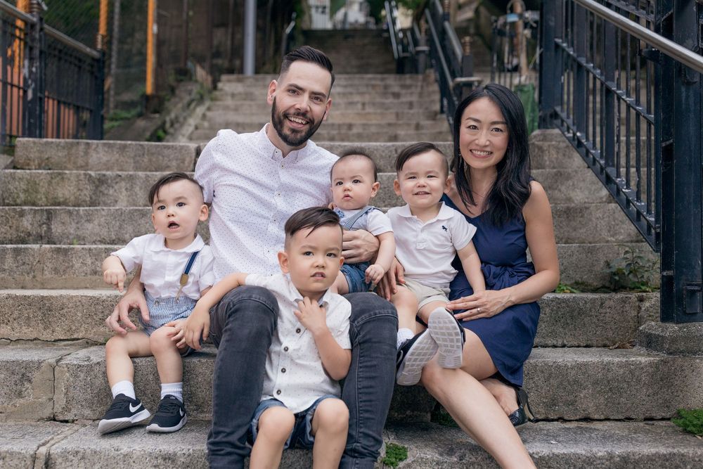 Happy family sitting on outdoor stone steps together enjoying a casual portrait session.