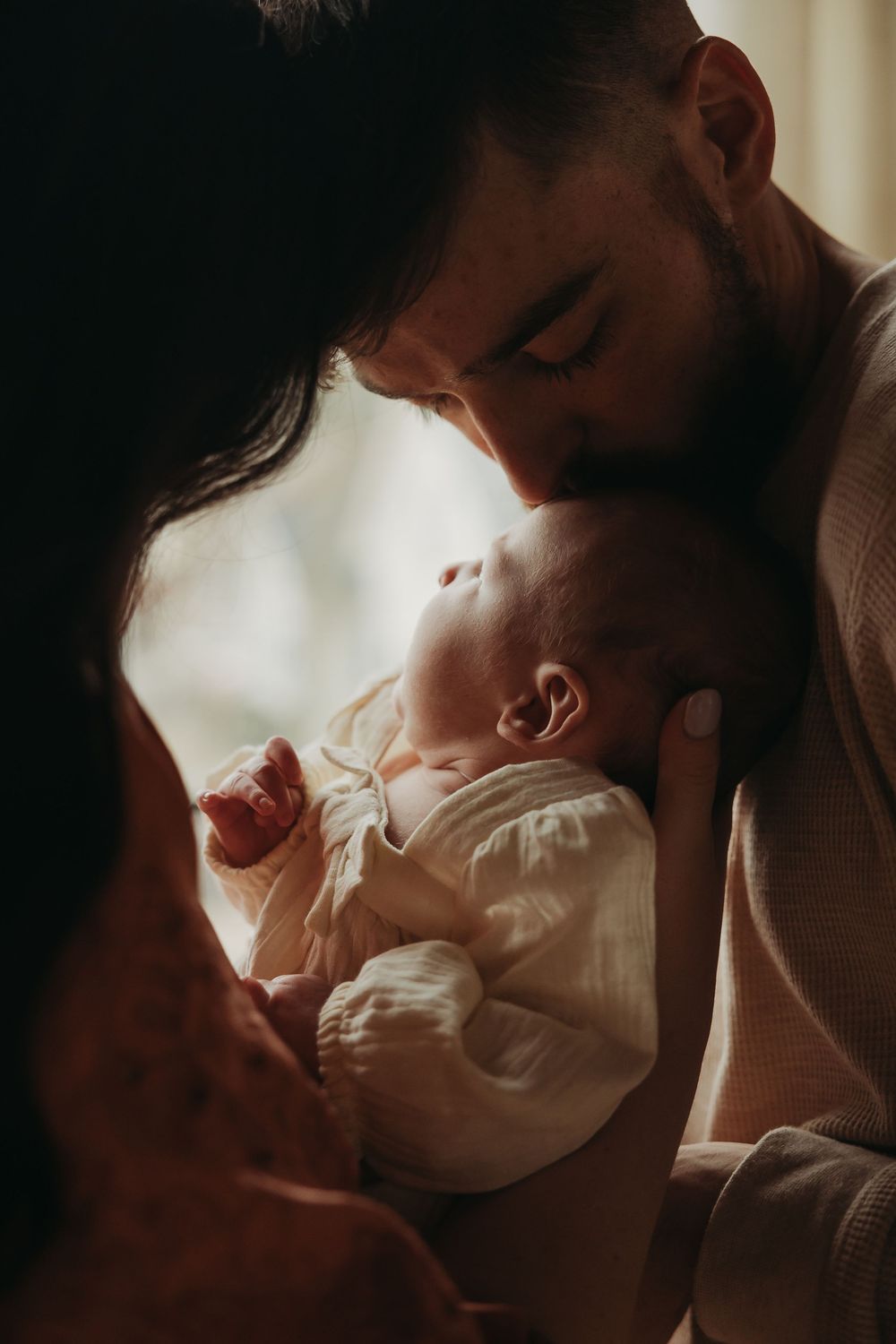 Tender moment between a parent and infant in soft lighting with warm vintage tones.