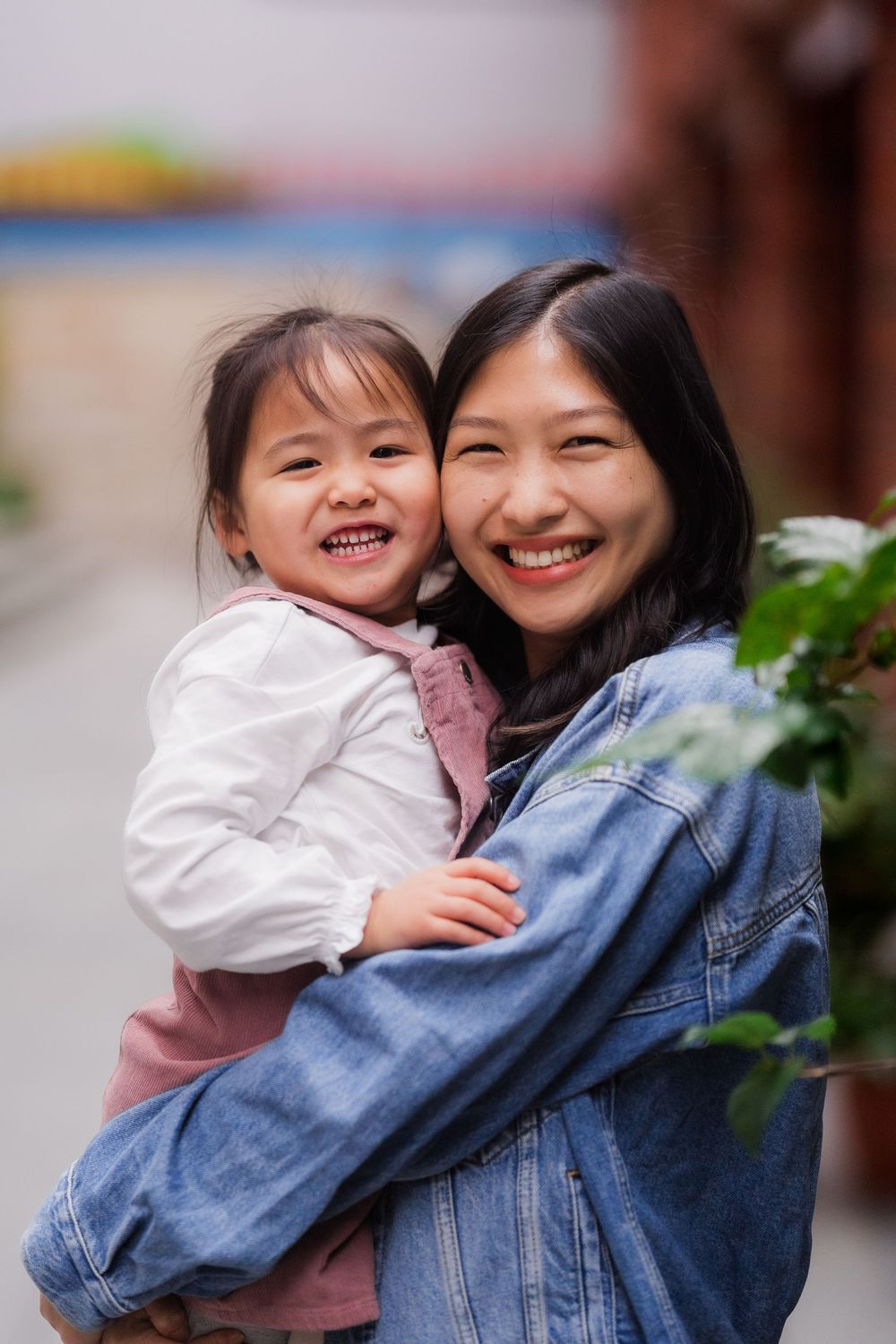 Heartwarming mother daughter embrace captured against outdoor greenery and natural light.