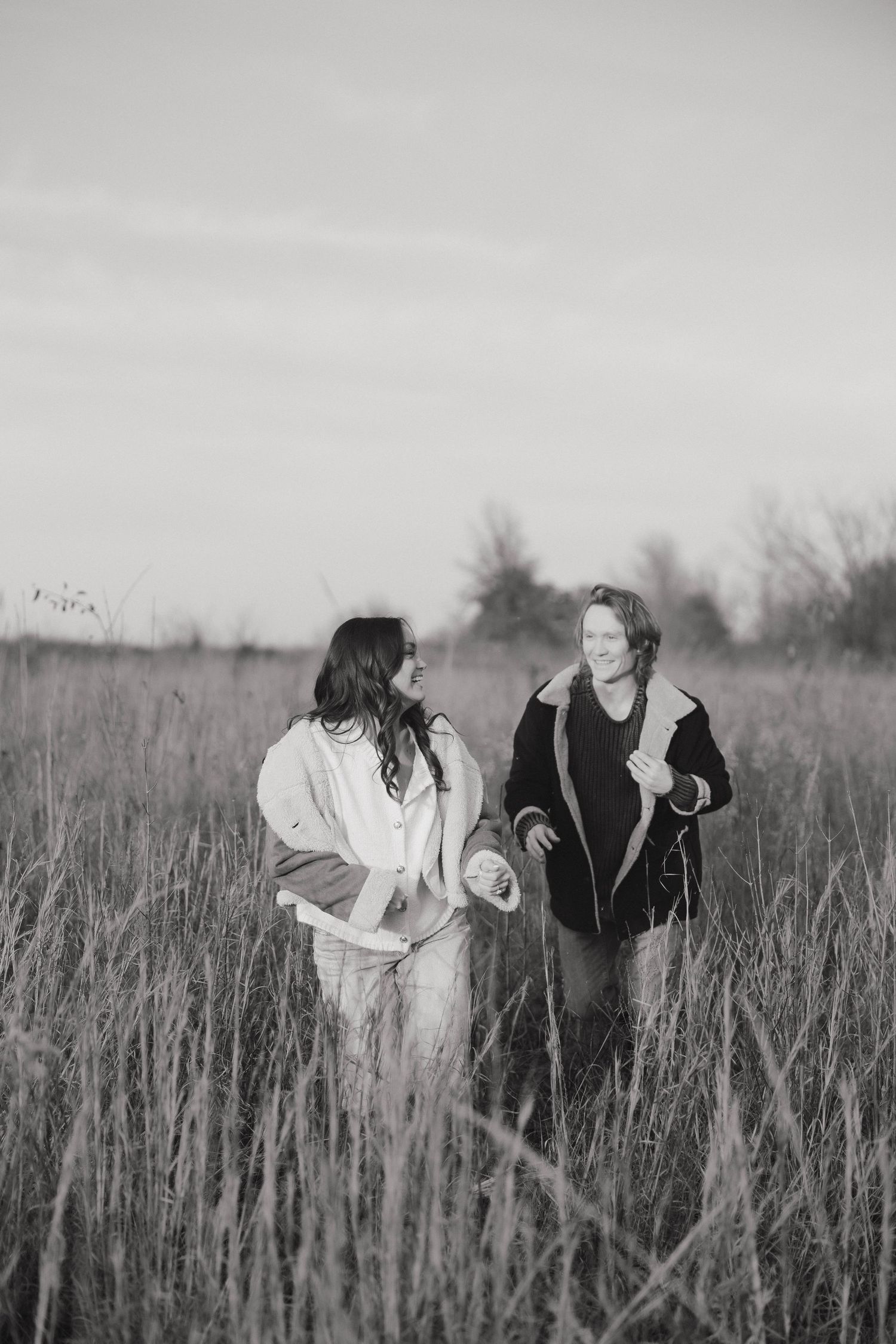 Black and white photo of people playing in a field of tall grass.