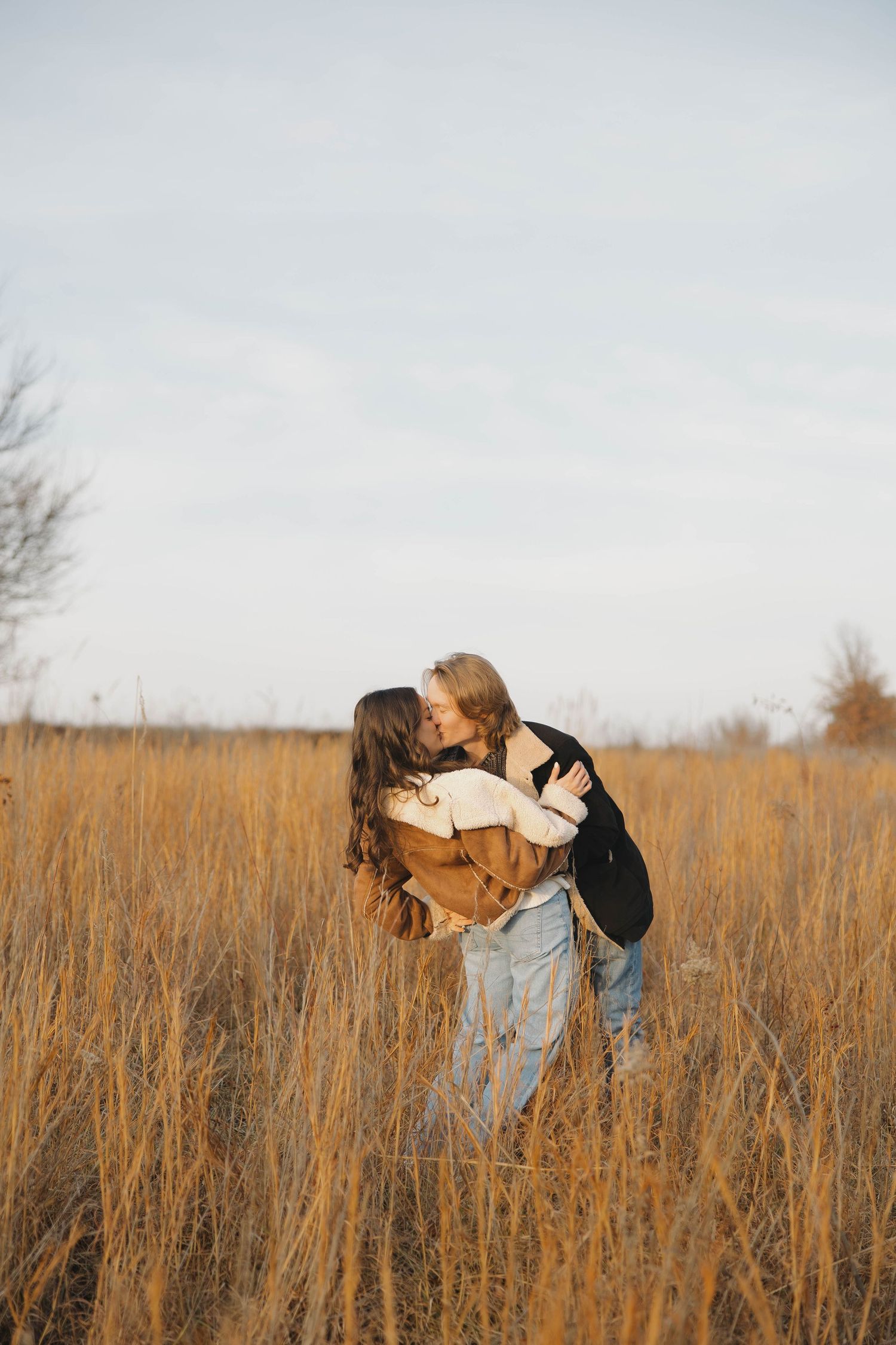 People sharing joyful moments together in a golden field of tall grass during sunset.