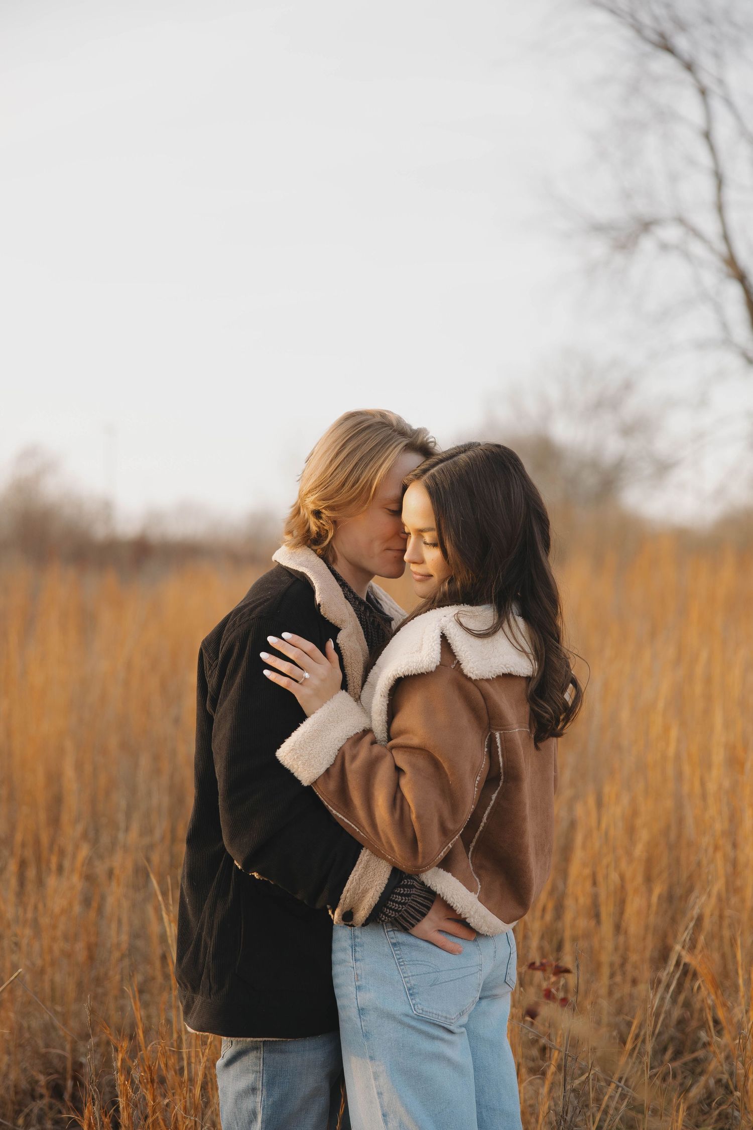 Intimate portrait of couple kissing in a rustic field during golden hour.