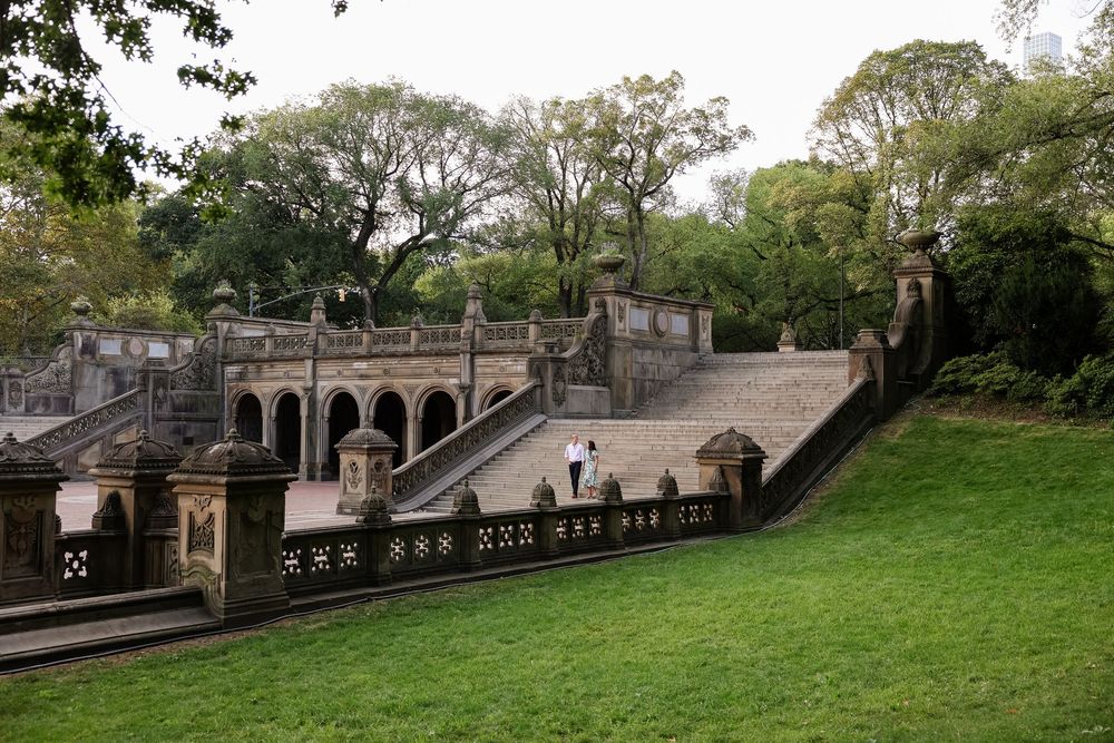 Stone archways and steps wind through a scenic park terrace with lush greenery and classic architecture.