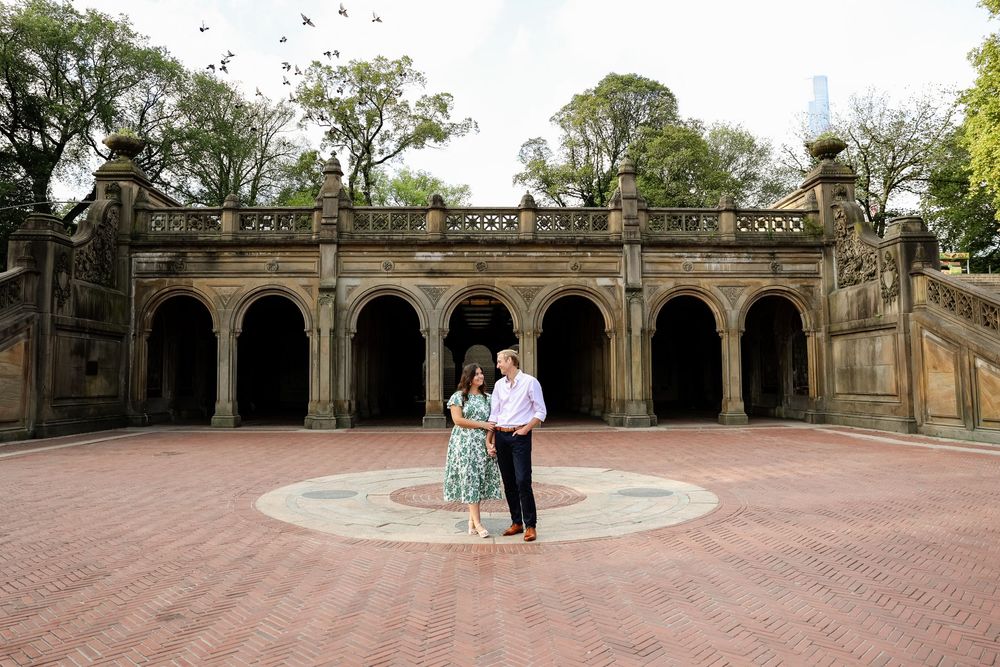 Couple walking through stone archways and arched corridors in a historic architectural setting.